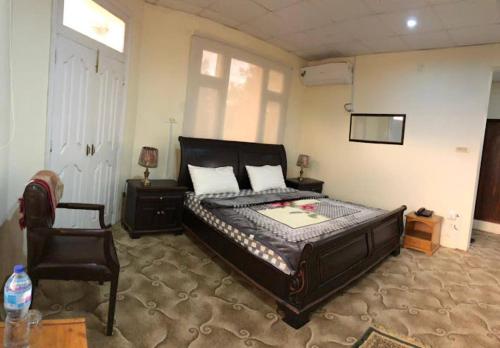 a bedroom with a large bed and a chair at Samson Inn in Dargai