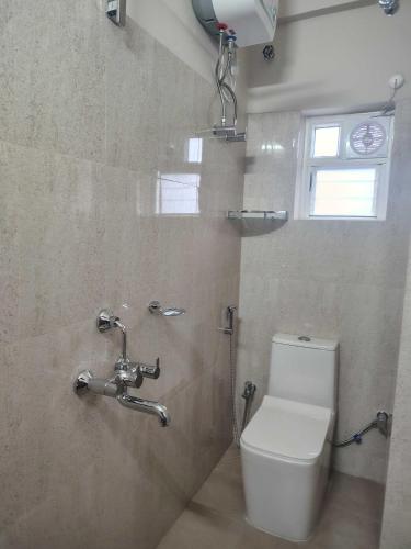 a bathroom with a toilet and a window at Townhouse Madhyamgram Chowmatha Bus Terminal Kolkata Formerly Star Guest House in Dohāri