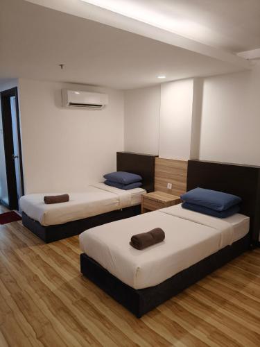 two beds in a room with wooden floors at Classy Studio Apartment (KBCP) in Kota Bharu
