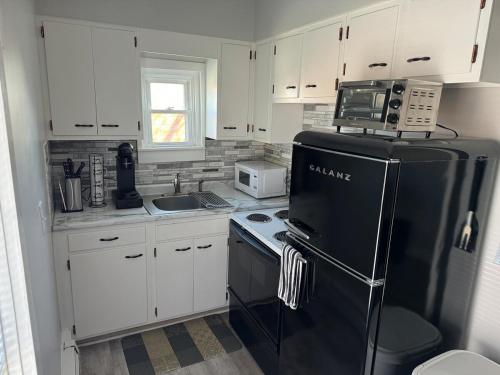 a kitchen with white cabinets and a black refrigerator at Downtown Willoughby Historic District Gem 3 in Willoughby