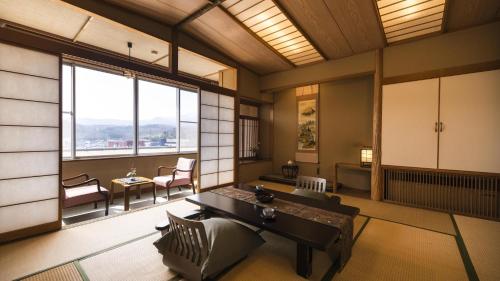 a living room with a couch and a table and windows at かっぱの宿旅館三治郎 in Zao