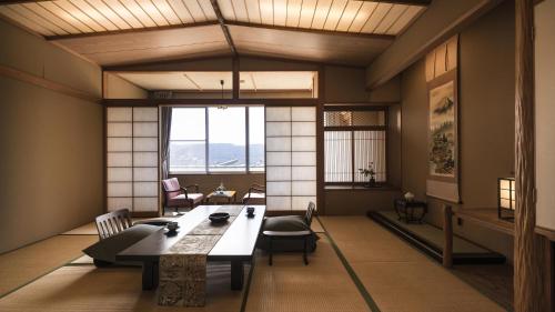 a room with a large table and chairs and windows at かっぱの宿旅館三治郎 in Zao