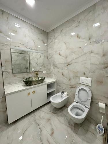 a white bathroom with a toilet and a sink at Vila Mullaj in Durrës
