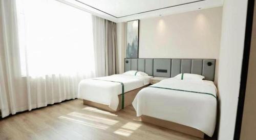 a bedroom with two beds and a large window at GreenTree Inn Langfang Sanhe South Yingbin Road Express Hotel in Sanhe
