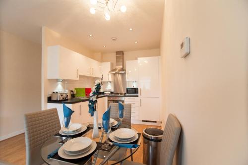 a dining room with a glass table and chairs at Station Suites in Watford