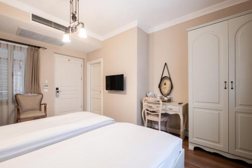 a white bedroom with a bed and a desk at Viento Alacati Hotel in Alacati