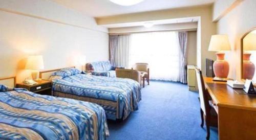 a hotel room with two beds and a desk at Yuzawa New Otani in Yuzawa