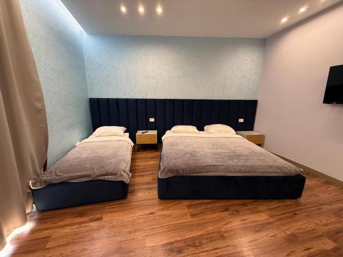 two beds in a bedroom with wooden floors at Blue Lagoon Stay 