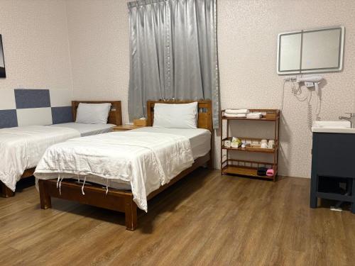 two beds in a room with wooden floors at 水源棧 in Fengyuan