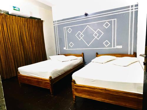two twin beds in a room with a wall at EESTEE Canal in Colombo