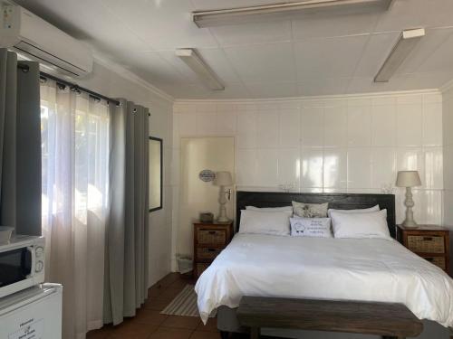 a bedroom with a white bed and a television at Karoo Huisie in Vanderbijlpark