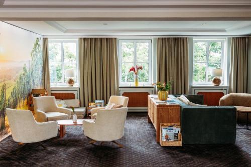a living room with a couch and chairs and windows at Landhotel Kauzenberg in Bad Kreuznach