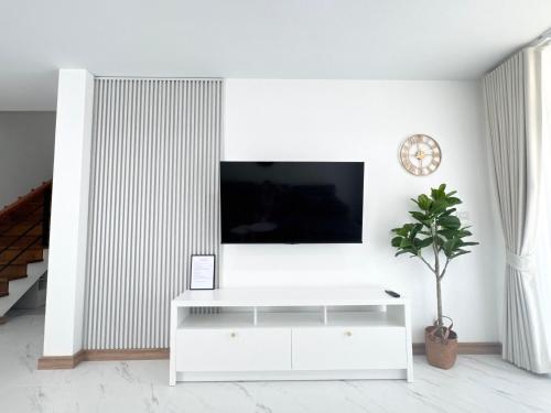 a white living room with a tv on a wall at CORNER STAY 210 Hatyai in Sathani Khlong Rian