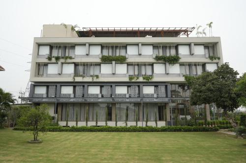 a tall white building with a lawn in front of it at Moolchand Resort in Muzaffarnagar