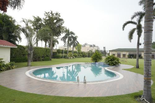 a swimming pool in a yard with palm trees at Moolchand Resort in Muzaffarnagar