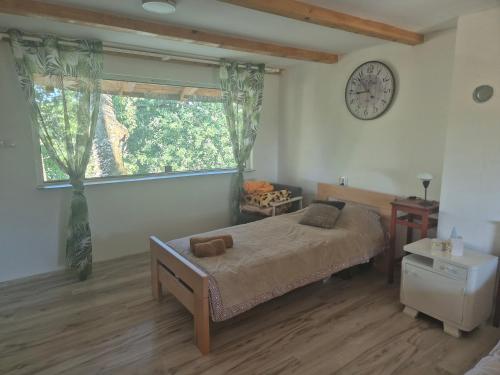 a bedroom with a bed and a clock on the wall at Vikendica na Tisi in Ada