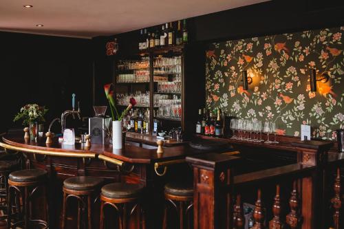 a bar with bar stools and a floral wall at Landhotel Kauzenberg in Bad Kreuznach