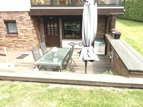 ルブミンにあるFerienwohnung Anni - DH - 24478のデッキにテーブルと傘が置かれたパティオ