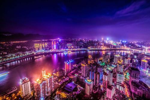 a city at night with a river and buildings at Pilot Hotel in Chongqing
