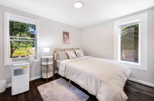 ein weißes Schlafzimmer mit einem Bett und zwei Fenstern in der Unterkunft Vintage Charm 3BR Home w Yard Pets Welcome in Shoreline