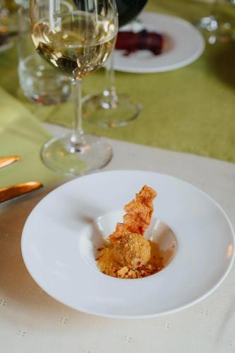 a white plate with a piece of food and a glass of wine at Hotel De Zevensprong in Binneheide