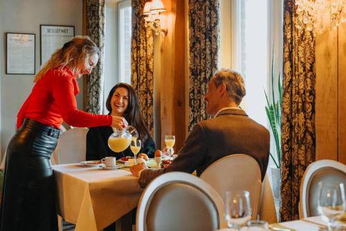 a woman serving a man at a table in a restaurant at Hotel De Zevensprong in Binneheide