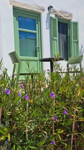a house with a green door and two chairs at Spice Suites-Lime in Amorgos