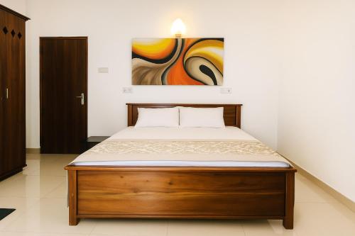 a bed in a bedroom with a painting on the wall at Ranaya Residence Kandy in Kandy