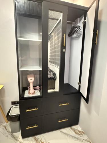a black cabinet with a mirror and a pink item in it at Unique Vibes Staycation in Punta