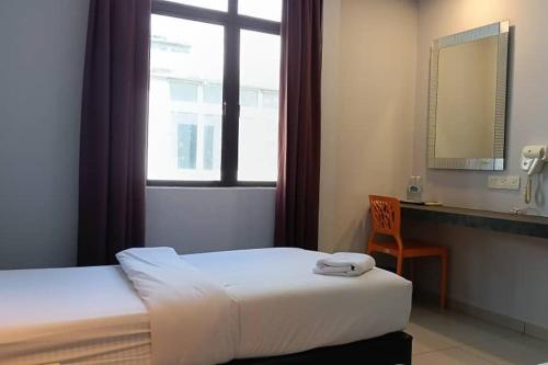 a bedroom with a bed and a window and a chair at Mars Hotel in Kuala Lumpur