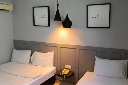 two beds in a room with a phone on the wall at Mars Hotel in Kuala Lumpur
