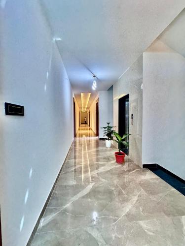 a hallway with white walls and a hallway with a plant at Hotel Sky Suites in Gurgaon
