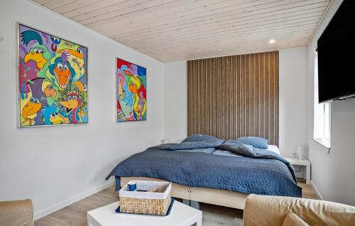 a bedroom with a bed with blue sheets and paintings at Stunning Apartment In Bogense With Wifi in Bogense