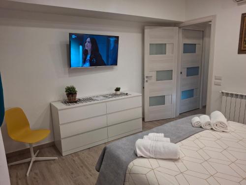 a bedroom with a television on a white wall at B&B Brezza Marina in Roccalumera