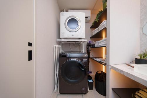 a washer and dryer in a closet with a microwave at クリスタルヴィラ南城 in Azama