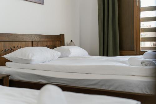 two beds in a bedroom with white sheets and pillows at Niki Apart Pension in Gheorgheni