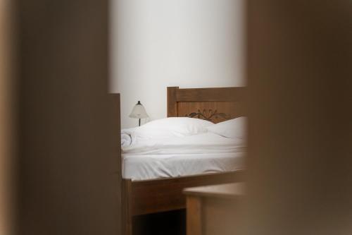 a bedroom with a bed with white sheets and a lamp at Niki Apart Pension in Gheorgheni