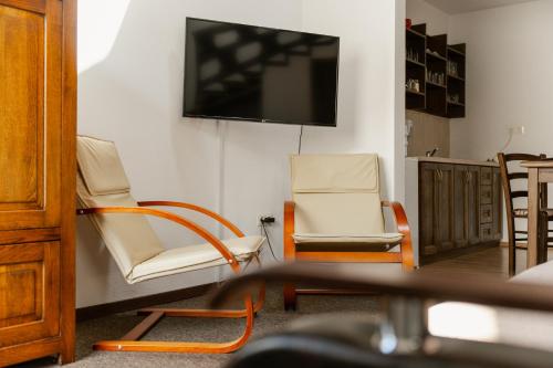 a living room with two chairs and a flat screen tv at Niki Apart Pension in Gheorgheni