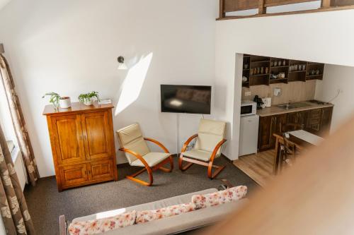 a living room with a couch and chairs and a kitchen at Niki Apart Pension in Gheorgheni
