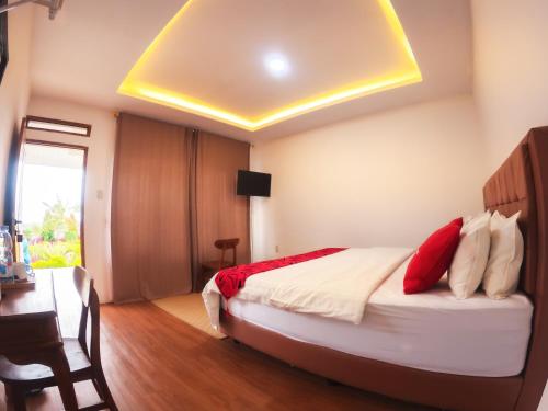a bedroom with a bed with red pillows and a desk at Noah Hotel Silangit in Siborongborong