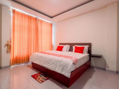 a bedroom with a bed with red pillows and a window at Noah Hotel Silangit in Siborongborong
