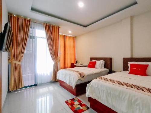 a hotel room with two beds and a window at Noah Hotel Silangit in Siborongborong