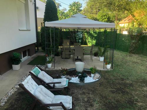 a patio with two chairs and a table with an umbrella at Apartment Vila MM Srce in Vrdnik