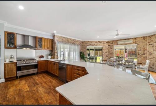 a large kitchen with wooden cabinets and a large white counter top at Family Dream Home in Burpengary East