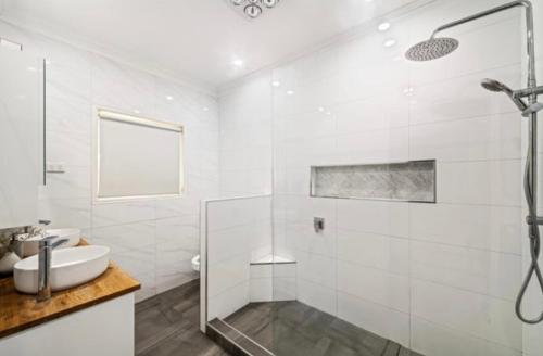 a white bathroom with a shower and a sink at Family Dream Home in Burpengary East
