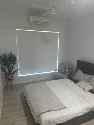 a bedroom with a bed and a window with a fan at Family Dream Home in Burpengary East