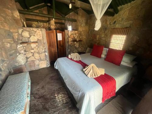 a bedroom with two beds in a stone wall at Sasa Safari Camp & Tours in Outjo