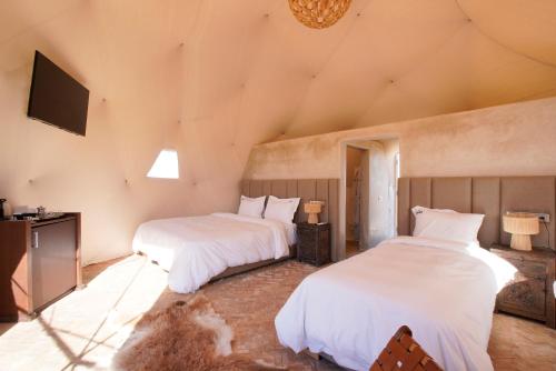 a bedroom with two beds and a television in it at The Ranch Camp in El Karia