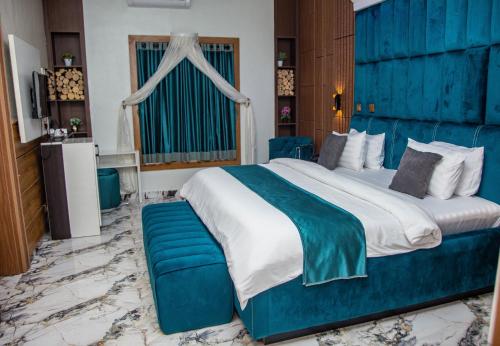 a bedroom with a large bed with a blue headboard at Cardiff Resort in Makurdu