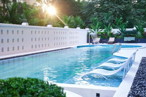 a swimming pool with a white fence and chairs in it at 西双版纳熙源国际酒店 in Jinghong